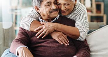 A seated man with a woman embracing him