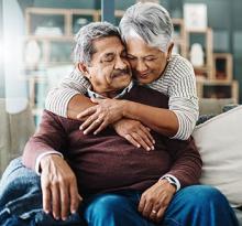 A seated man with a woman embracing him